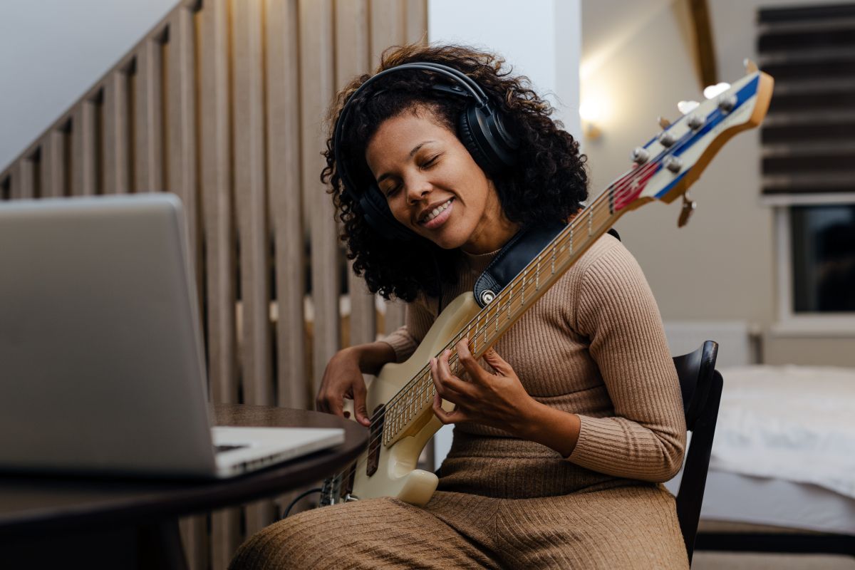 A woman with an laptop in front of her taking online Bass Guitar lessons